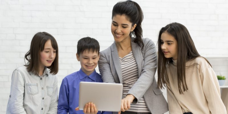 teacher-and-kids-looking-on-tablet-computer-during-Z93CVLY.jpg